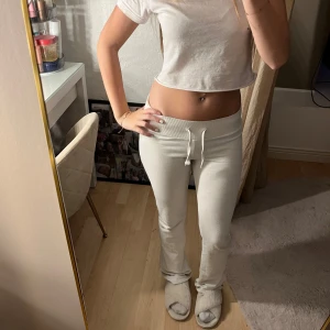 Vita mjukisbyxor från Nelly XXS - Supermjuka vita mjukisbyxor från Nelly i storlek XXS. Byxorna har hög midja, ribbad linning med snörning och raka ben med lätt utsvängd passform. Perfekta för chill dagar hemma eller när du vill vara bekväm men ändå snygg.