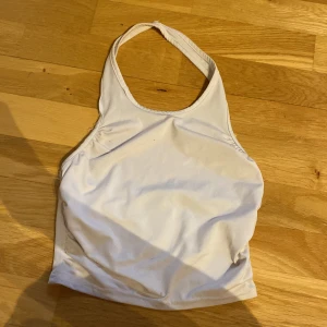 Vit halterneck linnetopp från SHEIN - Säljer en vit halterneck linnetopp från SHEIN i storlek 10-11 år. Toppen har en enkel och stilren design med smala axelband som knyts bakom nacken. Perfekt för varma dagar och enkel att matcha med jeans eller shorts.