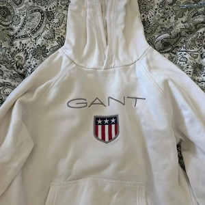 Vit hoodie från GANT med broderad logga - Vit hoodie från GANT med broderad logga och sköld på bröstet. 