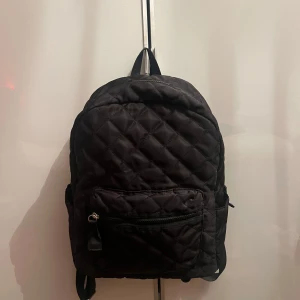 Ryggsäck, Don Donna - Säljer en svart quiltad ryggsäck från Don Donna. Väskan har ett stort huvudfack, ytterficka med dragkedja och zebramönstrat innerfoder. Har inte skador eller fläckar!