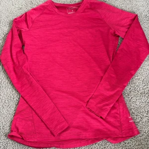 Rosa långärmad träningströja Energetics - Snygg långärmad träningströja från Energetics i en stark rosa färg. Tröjan har en smickrande passform, rund halsringning och är tillverkad i ett lätt och stretchigt syntetmaterial som andas. Perfekt för löpning, gym eller andra sportaktiviteter.