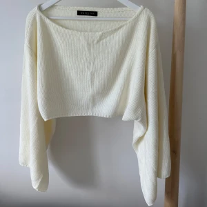 Vit croppad stickad tröja White Fox - Superfin vit croppad stickad tröja från White Fox med bred halsringning och långa, lösa ärmar. Mjuk och bekväm, passar till både jeans och kjol.