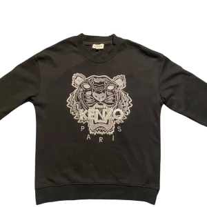 Kenzo sweatshirt - Säljer min snygga Kenzo-tröja i klassisk svart med det ikoniska tigerbroderiet. 🧵 Broderad logga “KENZO PARIS” 📏 Storlek: M (normal i storlek) 👕 Skick: Väldigt bra – sparsamt använd, inga fläckar eller hål Perfekt för dig som gillar streetwear med en stilren touch. Nypris ca 2000 kr.  📬 Skickas snabbt eller kan mötas upp i Göteborg