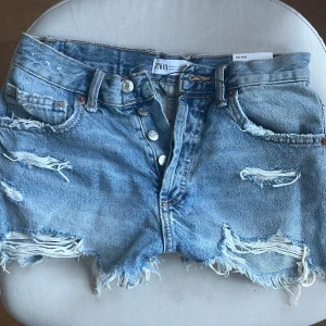 jeansshorts med slitningar - Säljer ett par ljusblå jeansshorts från Zara med råa kanter och slitningar   Helt nya