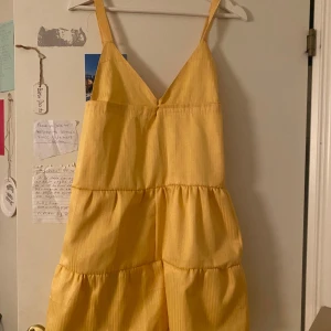 Gul volangklänning med smala axelband - Superfin gul klänning med smala axelband och volanger i flera lager. Fått i present vet därav ev märke