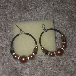 Stora örhängen med bruna pärlor - Snygga stora hoops med bruna pärlor i olika storlekar och silvriga detaljer. Örhängena har en svart båge och coola metallinslag som ger en unik look. Perfekta för att lyfta din outfit med lite extra bling. PRIS KAN DISKUTERAS!