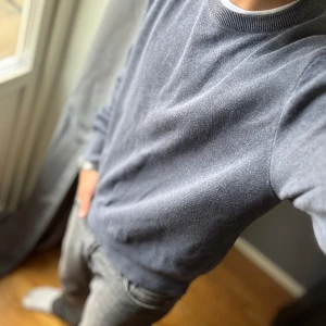 Grå stickad tröja från Zara - Säljer en stilren grå stickad tröja från Zara i storlek M. Tröjan har rund halsringning, ribbade muddar och är långärmad. Perfekt för lager-på-lager och funkar till både jeans och chinos. 