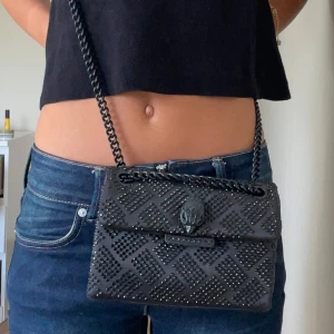 Svart glittrig väska, Kurt Geiger - Så snygg och elegant väska ifrån Kurt geiger! Som passar super bra till både Fester och till vardags. Väskan är i fint skick men har lite slitningar på knapparna och även lite på kedjan men är verkligen inget som syns! Har även lossnat några få stenar, men inget man lägger märke till heller! Kommer även med stenar! Säljer då den inte kommer till så mycket användning.💞💞