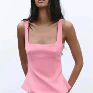 Rosa linnetopp med fyrkantig ringning - Supersnygg rosa linnetopp med breda axelband och fyrkantig ringning. Toppen har en figurnära passform upptill och faller lätt nedtill, perfekt för en trendig och fräsch look. Enkel att matcha med både jeans och kjol.