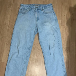 Ljusblå jeans från fsbn, baggy fit - Säljer ett par ljusblå jeans från fsbn i rak modell. Klassisk femficksdesign, normal passform och midja. Jeansen är tillverkade i bomull och har en snygg, enkel look som passar till det mesta. Perfekt för dig som gillar en clean och avslappnad stil.