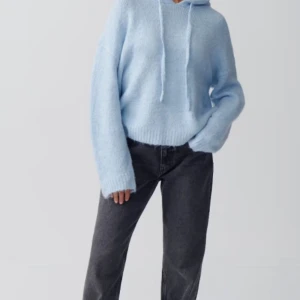 Ljusblå stickad hoodie - Mysig ljusblå stickad hoodie med en avslappnad passform. Den har en klassisk huva med dragsko och långa ärmar. Perfekt för kyliga dagar.