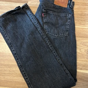 Svarta Levis 501 jeans - Säljer ett par klassiska svarta Levis 501 jeans. De har en knappgylf och fem fickor. Perfekta för en stilren look. Passar till det mesta och är ett måste i garderoben. De har storlek W33 L33
