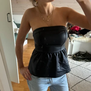 Svart bandeau topp - Så fin peplum topp i skinnimitation. Storlek XS