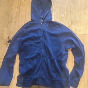 Blå hoodie med dragkedja - Säljer en blå Ralph lauren hoodie med dragkedja och huva. Tröjan har långa ärmar och en praktisk ficka framtill. Perfekt för en avslappnad stil.