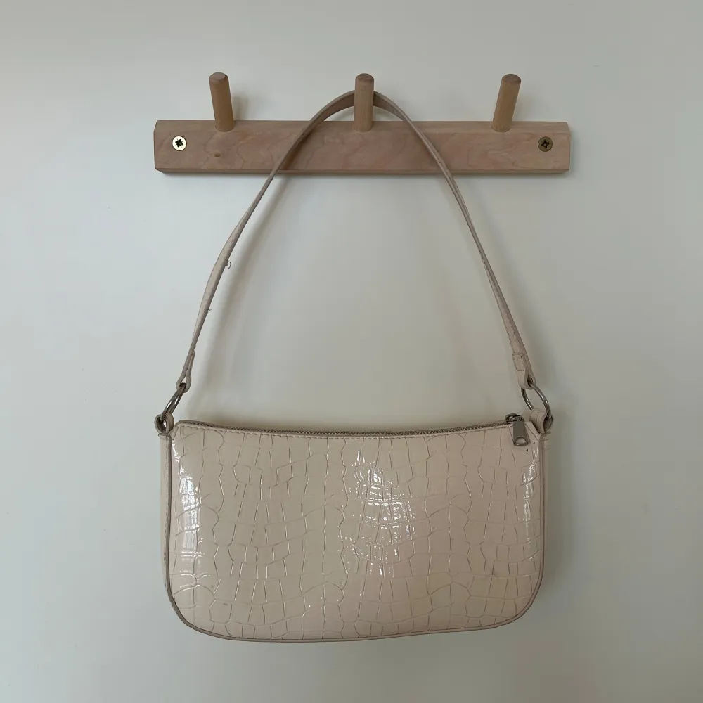 Snygg beige axelväska med krokodilmönster och dragkedja. Perfekt för att ge din outfit en stilren touch. Väskan har en enkel design med en justerbar axelrem. Är dock lite smutsig men det går att ta bort 🩷🩷. Laukut & Käsilaukut.