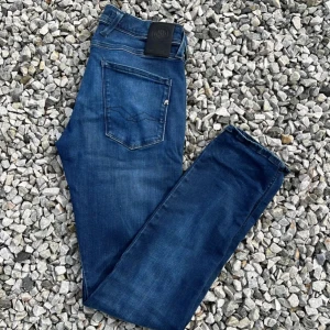 Blå jeans från Replay - Snygga blå jeans från Replay i modellen Anbass. De har en klassisk femficksdesign. Perfekta för en stilren look. Skriv gärna om du har en fundering😉