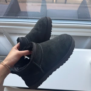 UGG W Classic Ultra Mini 8 Black - Köpta i december 2024 så väldigt nya. Endast använda måttligt då de var för stora. Inte använda i snö då jag bor i Malmö där det knappt snöar. Behöver borstas av i och med lite damm och dylikt och har ett litet veck (se bild) annars i gott skick. Nypris 2199 kr på NK