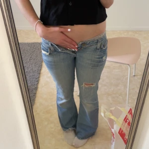 Blå bootcut jeans - Säljer ett par blå bootcut jeans med slitna detaljer och låg midja. Jeansen var tyvärr för små för mig🫠 Midjemått: 37 Innerbenslängd: 79