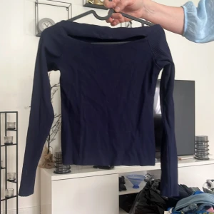 Mörkblå långärmad topp - En mörkblå långärmad topp med en offshoulder-design. 