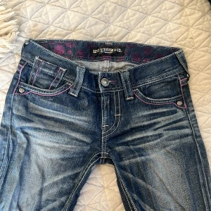 Levi's jeans med rosa sömmar - Snygga Levi's jeans i blå denim med unika rosa sömmar. De har en klassisk femficksdesign och en knappgylf. Perfekta för en avslappnad stil med en twist.