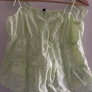 Ljusgrön topp/linne - Jättesöt ljusgrön topp med smala axelband och volangdetaljer. Toppen har en luftig passform och passar fint med tex jeansshorts. Aldrig använd.