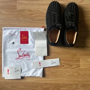 Svarta sneakers med nitar från Christian Louboutin - Snygga svarta loubs med röd sula och nitar i otroligt bra skick då dem ändast är använda ett fåtal gånger och är lite smutsiga på sulan. Det som medföljs syns på sista bilden. (Box medföljer ej), därav priset.