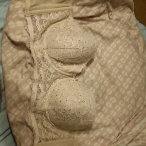 Beige spets-bh från H&M - Säljer en elegant beige bh från H&M med vacker spetsdetalj. Bh:n har en klassisk design med bygel och justerbara axelband för bästa passform. Perfekt för att ge en feminin touch till din garderob.