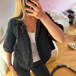 Svart kavaj/jacka med trekvartsärm - Snygg svart kavaj/jacka med trekvartsärm och knappar framtill. Perfekt för en stilren look. Passar bra till både jeans och kjol. Finns en liten defekt 💕Passar s-m