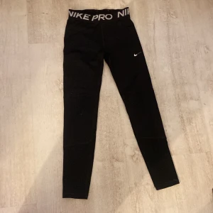 Svarta leggings från Nike Pro - Snygga svarta leggings från Nike Pro med hög midja och elastisk linning. Perfekta för träning med en stilren design och Nike-logga på benet. Bekväma och flexibla för alla typer av rörelser.