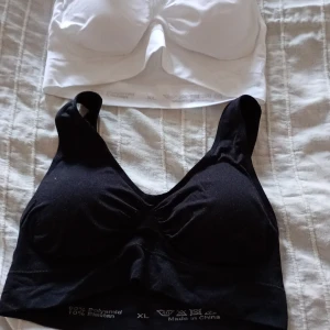 Svart och vit linnetopp i syntetmaterial bh - Två bekväma linnetoppar i svart och vitt. Tillverkade av 90% polyamid och 10% elastan för en stretchig passform. Perfekta för vardagsbruk eller träning.bh.