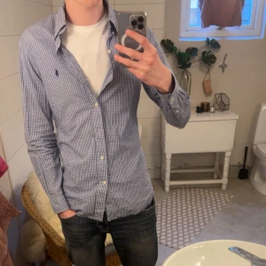 Blåvit skjorta från Polo Ralph Lauren - Snygg rutig skjorta från Polo Ralph Lauren i blått och vitt. Skjortan har en broderad logga på bröstet och är slim fit. Perfekt för en stilren look.