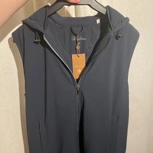 Stenströms väst - Snygg mörkblå väst från Stenströms med dragkedja och huva. Perfekt för lager-på-lager-stil. Västen har en stilren design och är tillverkad i ett mjukt material. Den modell säljs inte längre. Skriv vid funderingar!