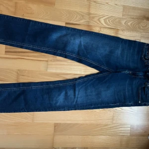 Mörkblå jeans från Tommy Hilfiger - Snygga mörkblå jeans från Tommy Hilfiger med klassisk design. De har en normal passform och är tillverkade i jeansmaterial. Perfekta för en stilren look.