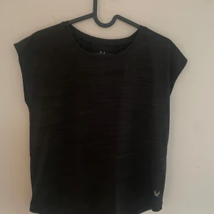 Svart tränings-tshirt från SOC - Svart t-shirt från SOC med diskret logga nere vid fållen. Modellen är enkel med rund hals och korta ärmar, perfekt för träning. Materialet är lätt och andas, vilket gör den skön att ha på sig när du rör på dig.