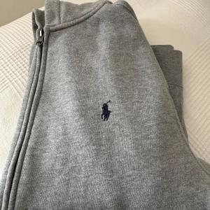 Grå hoodie från Polo Ralph Lauren - Välvårdade grå hoodie från Polo Ralph Lauren med dragkedja och huva. Klassisk logga broderad på bröstet. Storlek XS. 