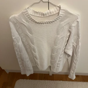 Vit kabelstickad tröja  - Säljer en vit kabelstickad tröja med grov struktur och breda muddar. Tröjan har rund halsringning och långa ärmar med snygga flätade detaljer längs ärmar och framstycke. Perfekt för sommarkvällarna. Storlek S, köpt på lager 157🤍