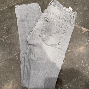 Ljusgrå Dondup George jeans  - Säljer mina as feta Dondup George jeans i modellen George Skinny Fit. Jensen har en as det design med några slitningar som gör de mycket snyggare! Säljer dessa för att de har blivit för små för mig. Priset är ej hugget i sten utan bara att höra av sig vid frågor o funderingar!🤩🤩