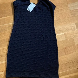 Svart kortklänning med strukturmönster!  - Ny med prislappar Säljer en svart kortklänning med diskret strukturmönster och smala axelband. Klänningen har en figurnära passform och är perfekt för dig som gillar en stilren look. Materialet känns mjukt och följsamt mot kroppen.