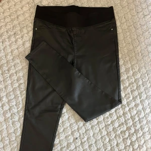 Svarta skinny byxor från Freequent - Svarta skinny byxor från Freequent i storlek XX-Large. Byxorna har hög midja med bred resår och en lätt glansig finish som ger en cool look. Fickor bak och fram, stretchigt material för extra komfort.