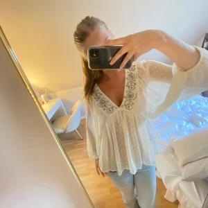 Vit blus med broderi från Zara - Supersöt vit blus från Zara med v-ringning och detaljer med pärlor och blommor vid halsen. Blusen är lätt transparent med prickigt mönster, har långa vida ärmar och flowig passform. Använd få gånger men i jättefint skick❤️