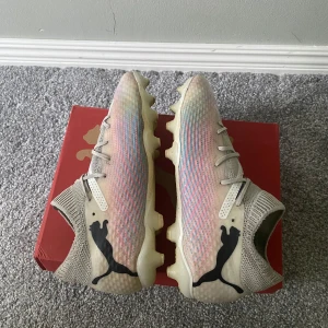 Puma Future 7 Pro fotbollsskor 38.5 - Snygga Puma Future 7 Pro FG/AG fotbollsskor i vitt med inslag av rosa och svarta detaljer. 