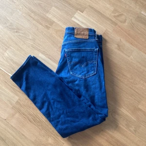 Levi's 511 blå jeans herr - Säljer ett par klassiska Levi's 511 jeans i blå denim. Modellen har en slim passform med raka ben och fem fickor. Jeansen har den ikoniska läderpatchen bak i midjan och röda Levi's-tag på bakfickan. Perfekta för dig som gillar en tidlös och clean look.