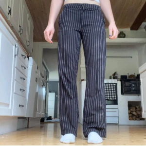 Randiga kostymbyxor från Kappahl - Snygga svarta kostymbyxor från Kappahl med vita vertikala ränder. Byxorna har normal passform, raka ben och klassisk midja. Perfekta för en stilren look. Det är inte riktiga fickor bak ❤️