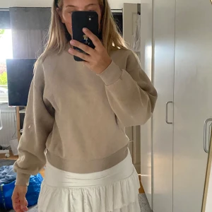 Beige sweatshirt i bomull - Enkel och stilren beige sweatshirt med rund hals och ribbade muddar. Tröjan har en loose passform och är tillverkad i mjuk bomull, perfekt för en chill och avslappnad look. Långärmad modell som passar året runt.