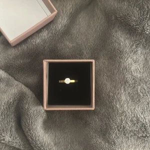 Ring Edblad - Snygg guldfärgad ring från Edblad med en rund, glittrande vit sten i mitten. Ringen har en klassisk och stilren design som verkligen poppar. Kommer i original ask, perfekt som present eller för att lyfta din egen stil. 