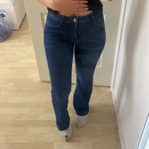 Blå bootcut jeans med normal passform - Snygga blå jeans med bootcut-snitt och klassisk femficksdesign. Jeansen har hög midja och är tillverkade i stretchigt denimtyg för en bekväm känsla. Perfekta för dig som gillar en tidlös look med lite utsvängda ben.