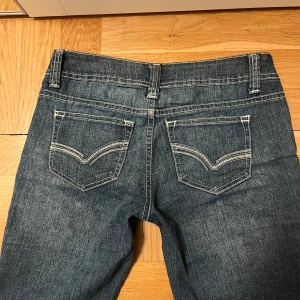 Lågmidjade bootcut/flare jeans  - Supersnygga lågmidjade bootcut/flare jeans med broderier på fickorna 💞 Från märket No bounderies! Köptes på Karlaplan loppisen men var tyvärr för små för mig så säljer vidare 😊skulle uppskatta att de är i storlek xs🫶🏼 midjemått: 37cm, innerbenslängd: 79cm