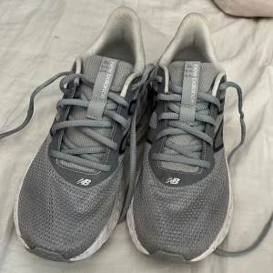 Grå New Balance 411 sneakers - Snygga grå New Balance 411 sneakers med mesh-ovandel och vita, dämpade sulor. Skorna har klassisk snörning och stora svarta N-loggor på sidorna. Perfekta för dig som gillar sport. Obs! Kommer ren tvättas innan dom skickas iväg! Använt cirka 4-5 gånger