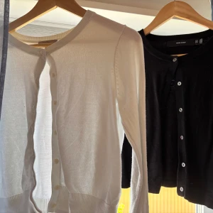 Vit och svart kofta med knappar - Klassisk vit och svart kofta med rund hals och knäppning framtill. Långärmad och i mjukt, tunt material som passar perfekt till lager-på-lager. Stilren och enkel design som funkar till många outfits. Den vita är i S från H&M och den svarta är Xs från vero moda
