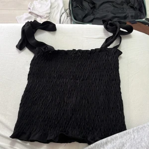 Svart smockad linnetopp med knytband - Topp från Ginatricot